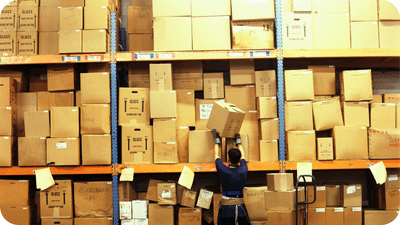 Man in a warehouse with shelves of cardboard boxes
