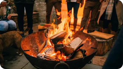 fire pit with wood on fire with people gathered around