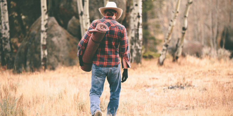 Best Wool Blankets for Bushcraft Man walking in the wilderness with a Wool Bushcraft Blanket