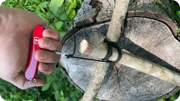 The author using a Swiss Army knife with hook extended to tighten a lashing on a bushcraft project