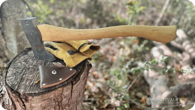 Jason's bushcraft axe in a stump with his gloves and the sheath laying on the stump